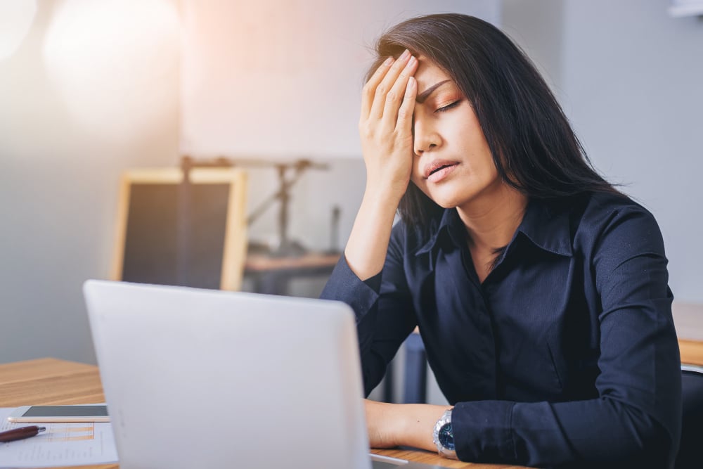 A woman suffers from a painful migraine at work