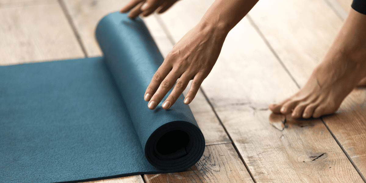 A person rolling a yoga mat out