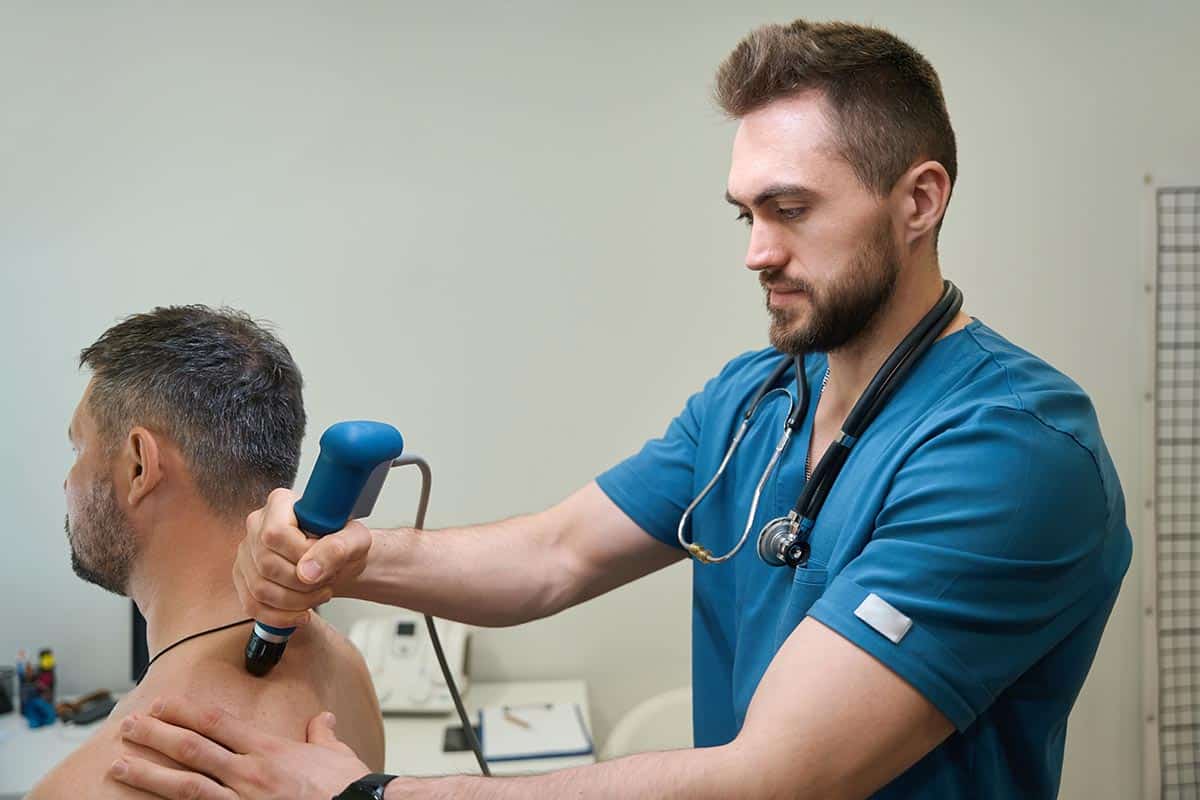 Experienced All American Medical therapy tech performs a Shockwave Therapy procedure on adult patient.